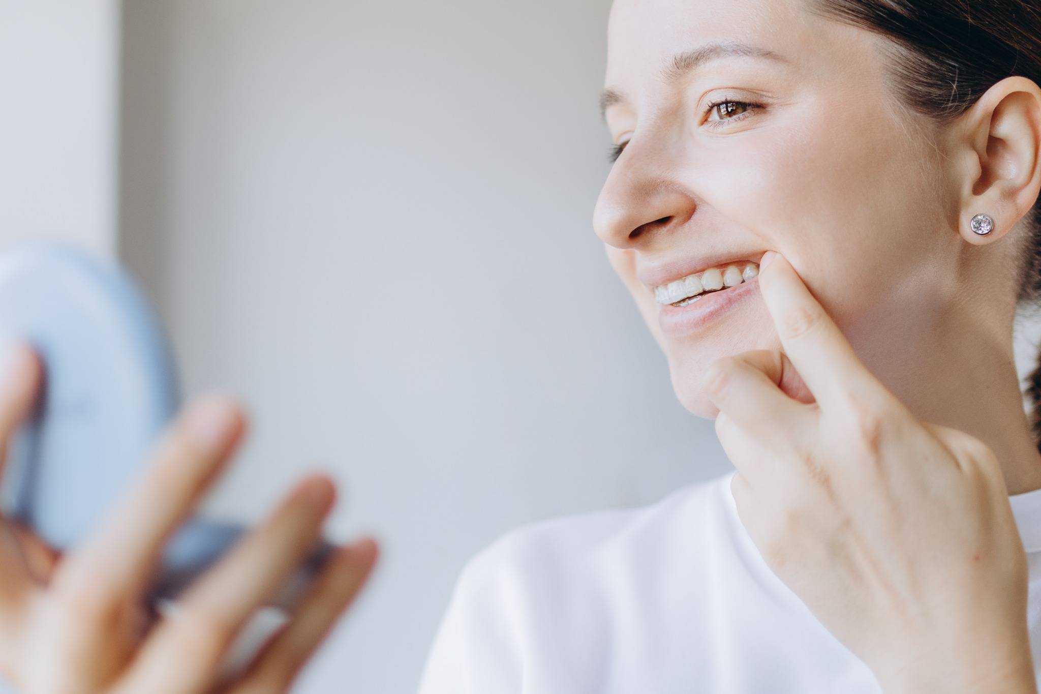 Frau schaut Zähne im Spielgel an