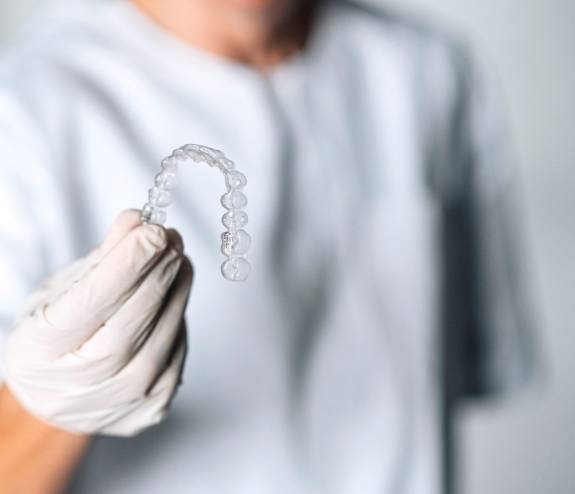 Mann in weißer Kleidung hält Zahnschiene