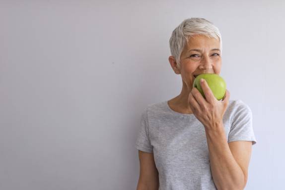 Lächelnde Frau mit schönen Zähnen und Apfel