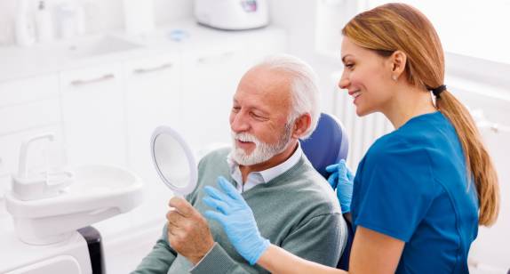 Zahnärztin mit älterem Patienten